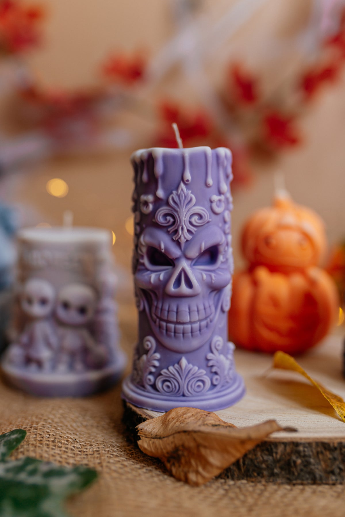 Tall purple skull pillar soy candle on a rustic wooden base.