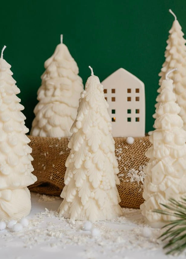 Creamy white soy wax candle shaped like a Christmas tree made of detailed leaves and berries, resembling a frosted winter tree.