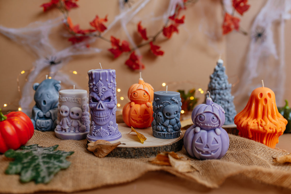 Halloween soy candle collection arranged in a row with pumpkins and autumn leaves.