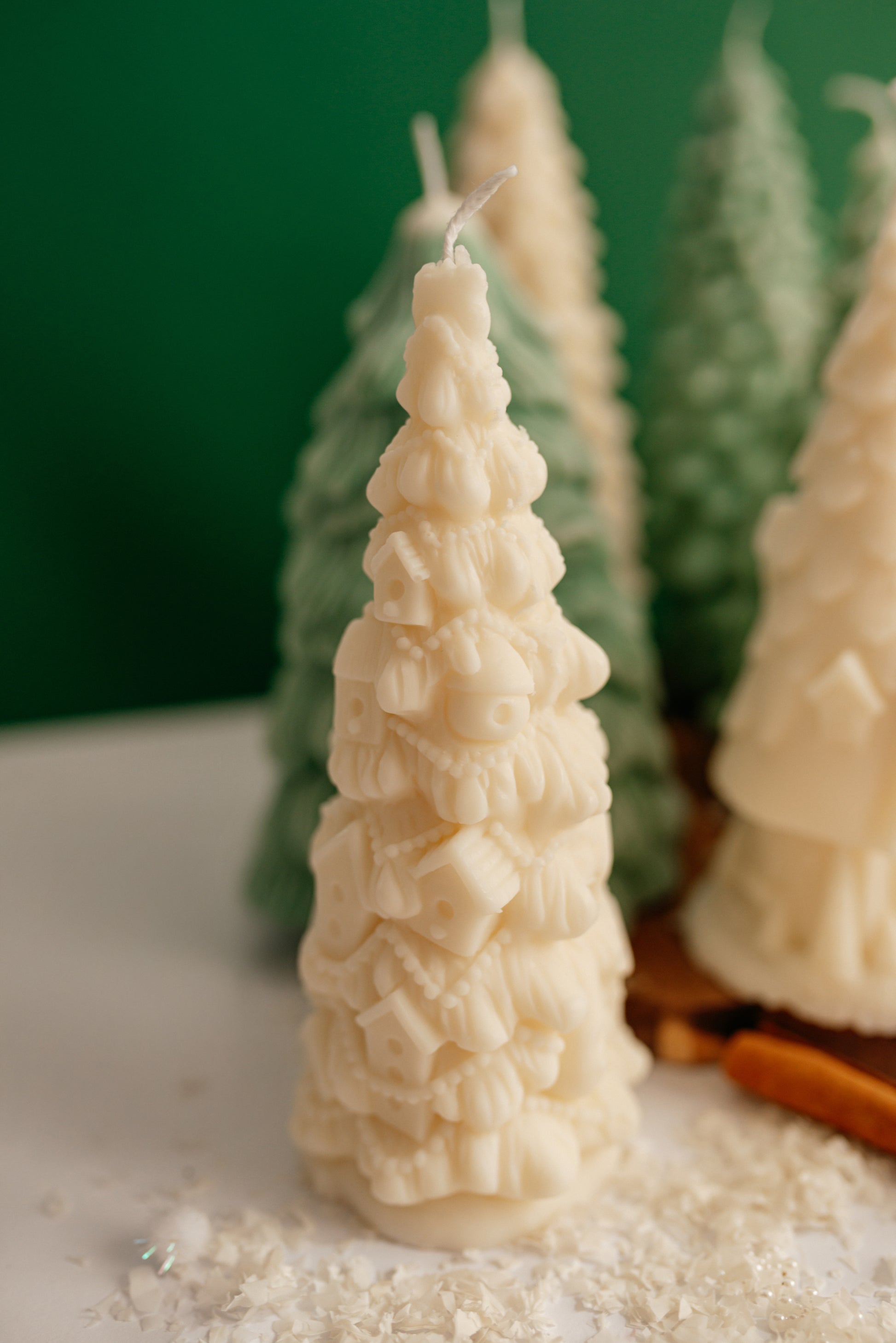 Close-up of a creamy white soy wax candle shaped like a Christmas tree covered in many small, detailed houses and decorations.