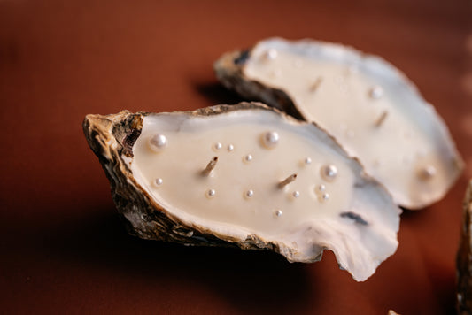 Two oyster shells with pearls on a brown background