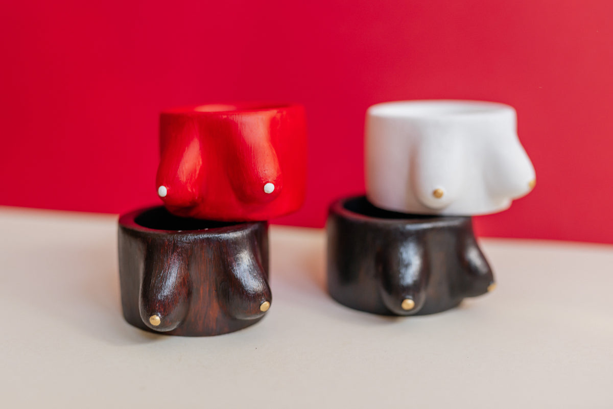 Pairs of Fiery Red, Smoked Walnut, Alabaster White, and Obsidian Gold plaster breast candle holders and jewelry dishes.